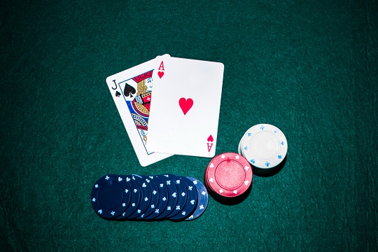 Jack of spade and heart ace card with casino chips stack on green table